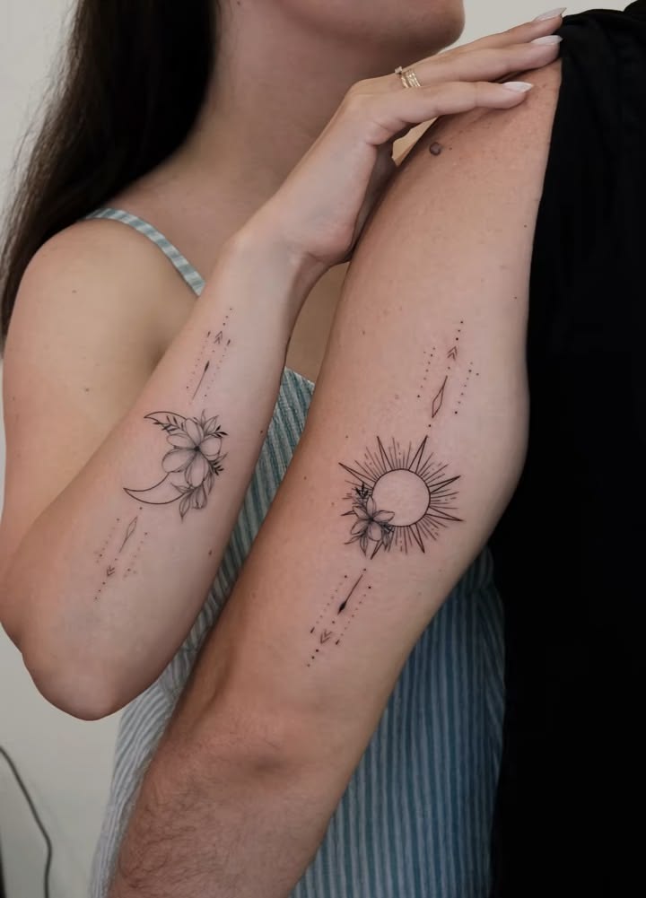 Fine-line floral crescent moon and rayed sun tattoos with dotted arrow details on two arms