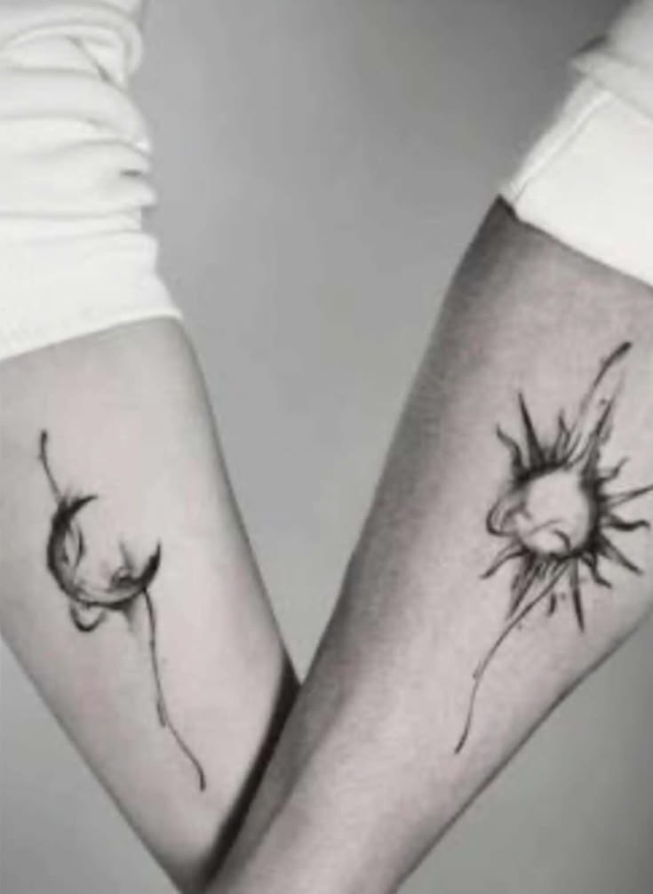 Matching ink wash tattoos of a crescent moon and a sun on two forearms in black and white