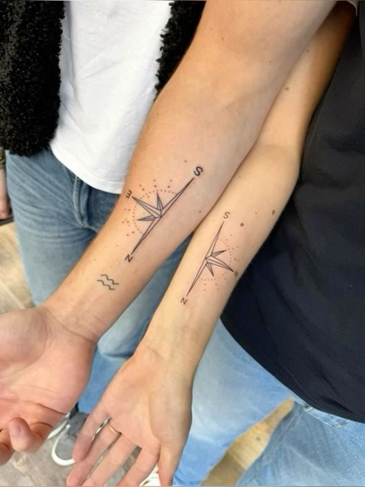 Matching forearm tattoos of a fine-line compass rose with dotted circles