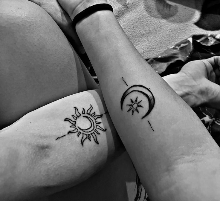 Simple bold outline sun with a moon and a crescent moon with a small sun on two forearms
