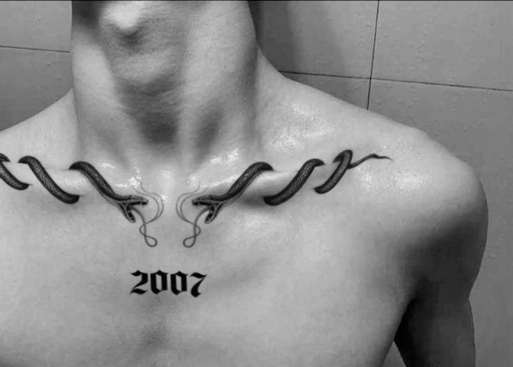 Black and white photo of two snakes wrapped along the collarbones with the year 2007 in blackletter