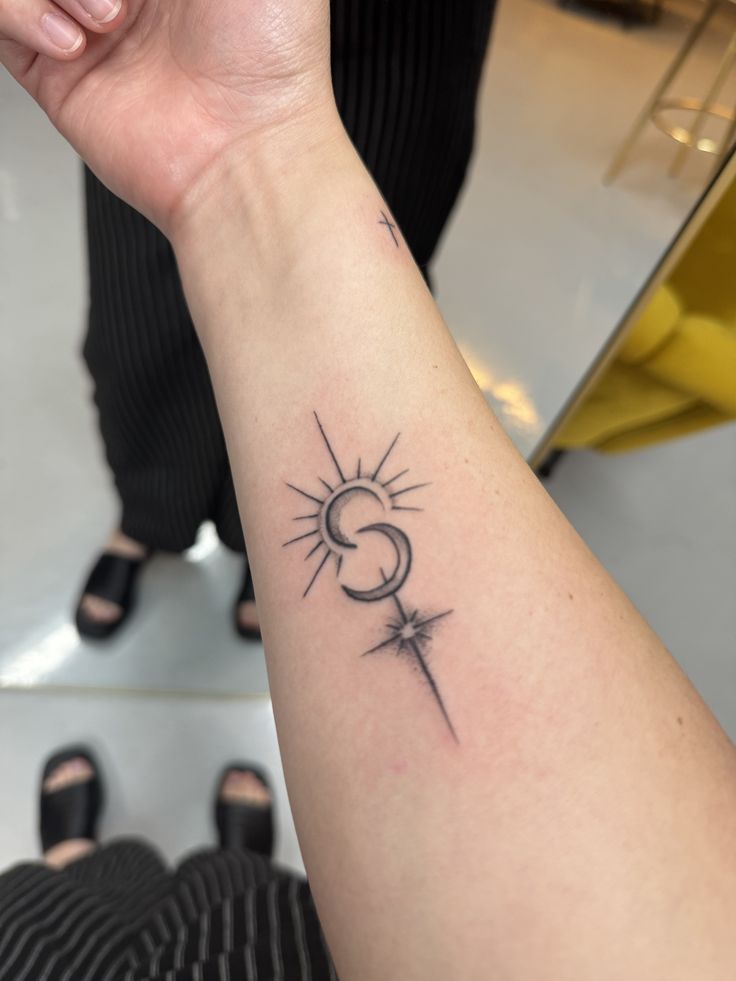Sun, crescent moon and star tattoo with sunrays on the inner forearm