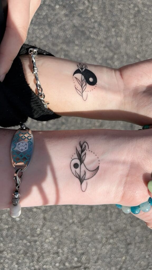 Matching yin yang couple tattoos with leaves and dotted lines on two wrists