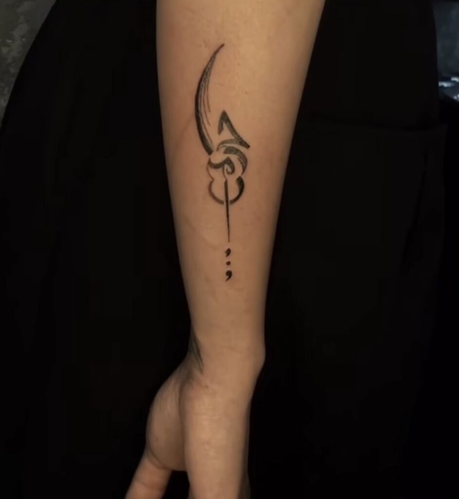 Abstract curved blade tattoo with a swirl and a small semicolon on the inner forearm