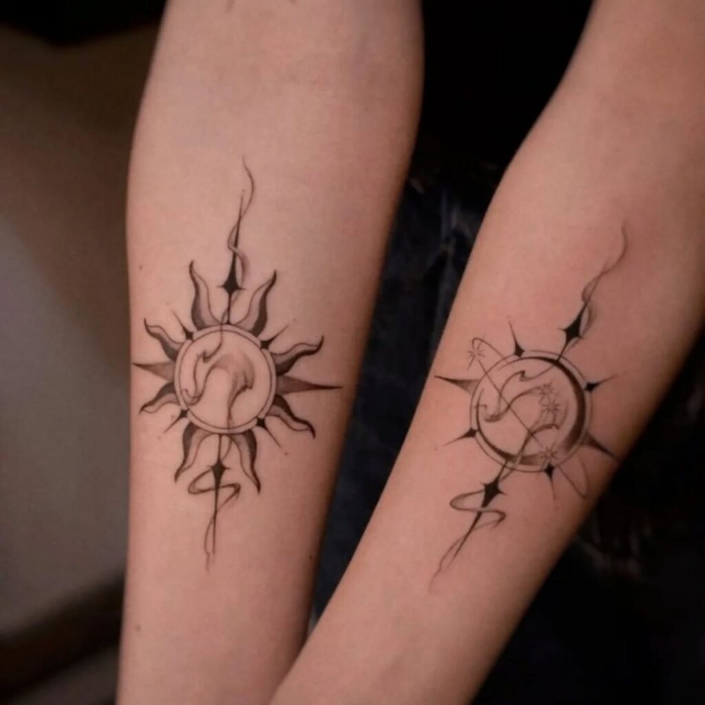 Matching sun and crescent moon tattoos with smoky lines and stars on two forearms