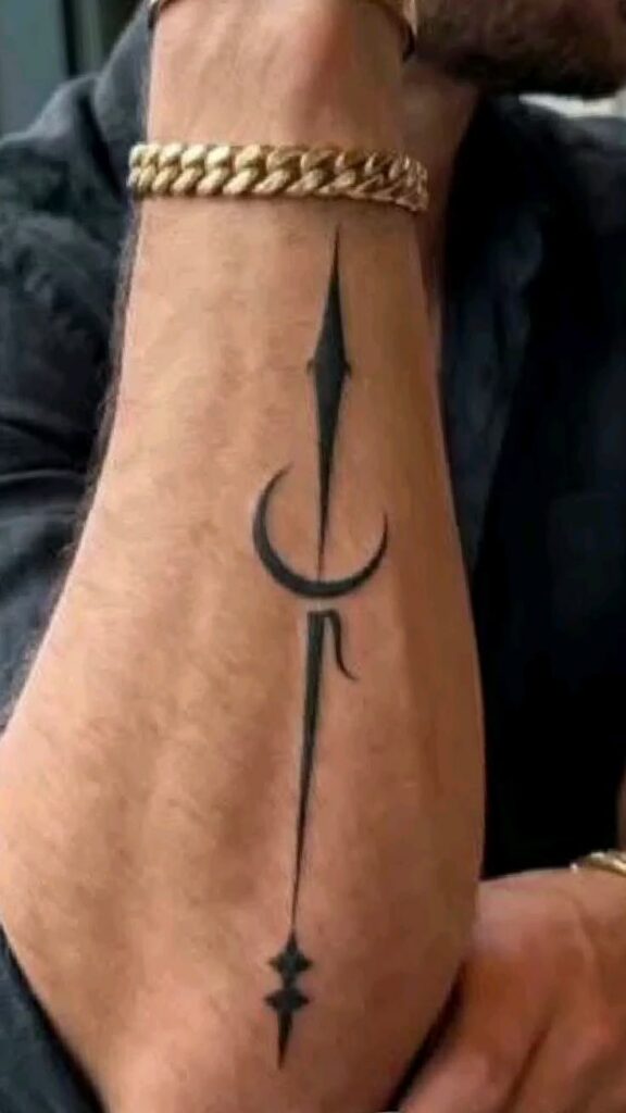 Black dagger and crescent moon forearm tattoo on a man wearing a gold chain bracelet