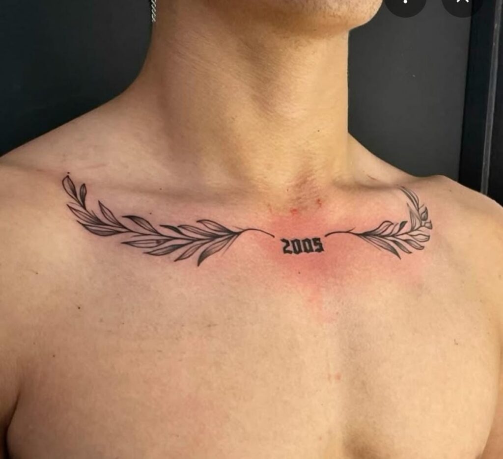 Laurel branch collarbone tattoo with the year 2005 in blackletter at the center of the chest