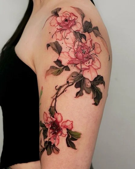 Fine-line magnolia and leaf tattoo on a woman’s inner upper arm