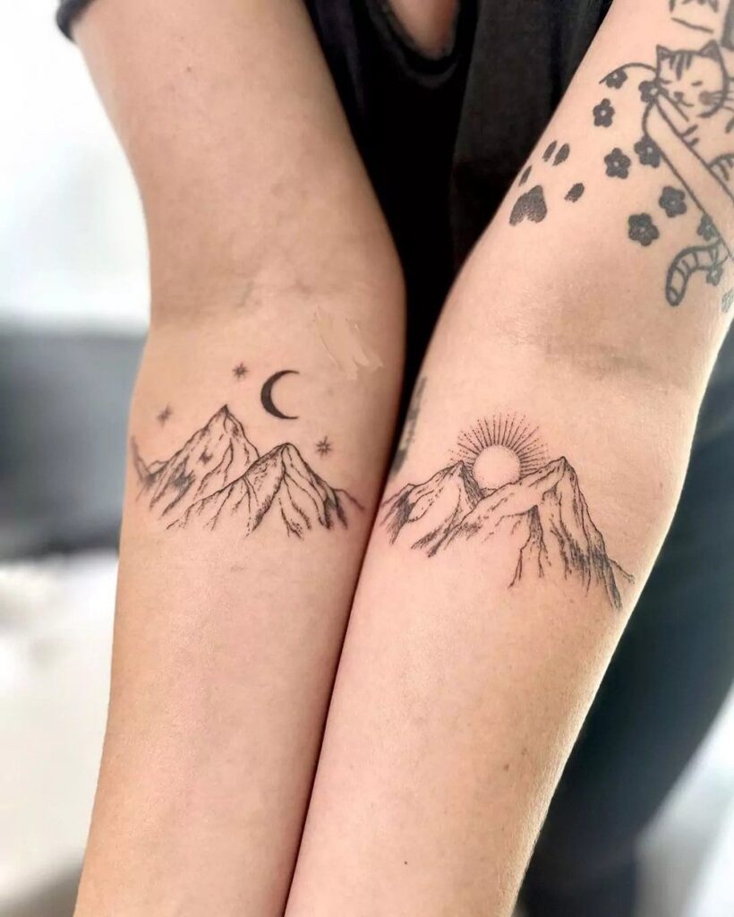Matching forearm tattoos of mountain peaks, one under a crescent moon and stars and one with a rising sun
