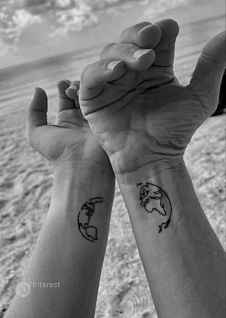 Two small wrist tattoos that each show half of a globe, forming one world when the wrists are together