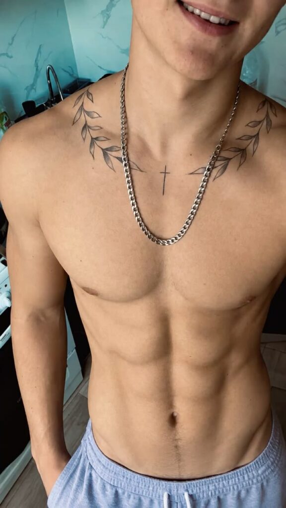 Olive branch, crown and cross made of the words Familia and Dios tattoo across a man’s collarbones