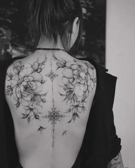 Fine-line black and grey peony tattoo with leaves on a woman’s thigh