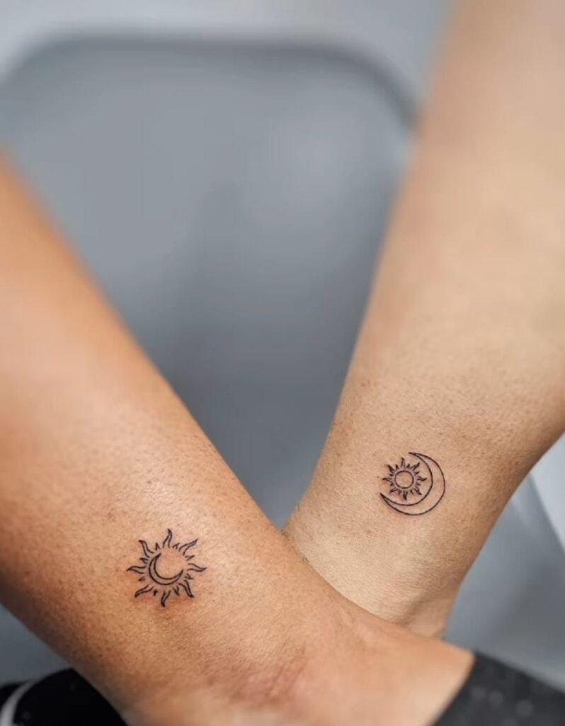 Small matching sun with moon and moon with sun outline tattoos on two crossed wrists